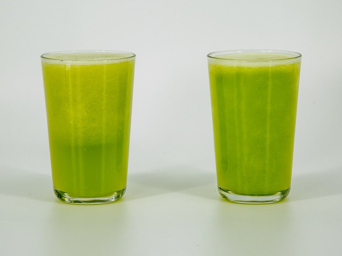 Two glasses of celery juice 20 minutes after pouring. The vacuum-off glass on the left has a pale layer on top; the vacuum-on glass on the right is still green throughout.