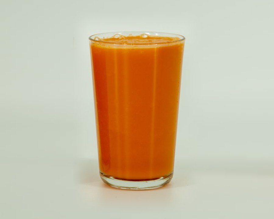 The same ingredients blended with the vacuum on, photographed 20 minutes after pouring. One uniform orange from top to bottom, with no separation line.